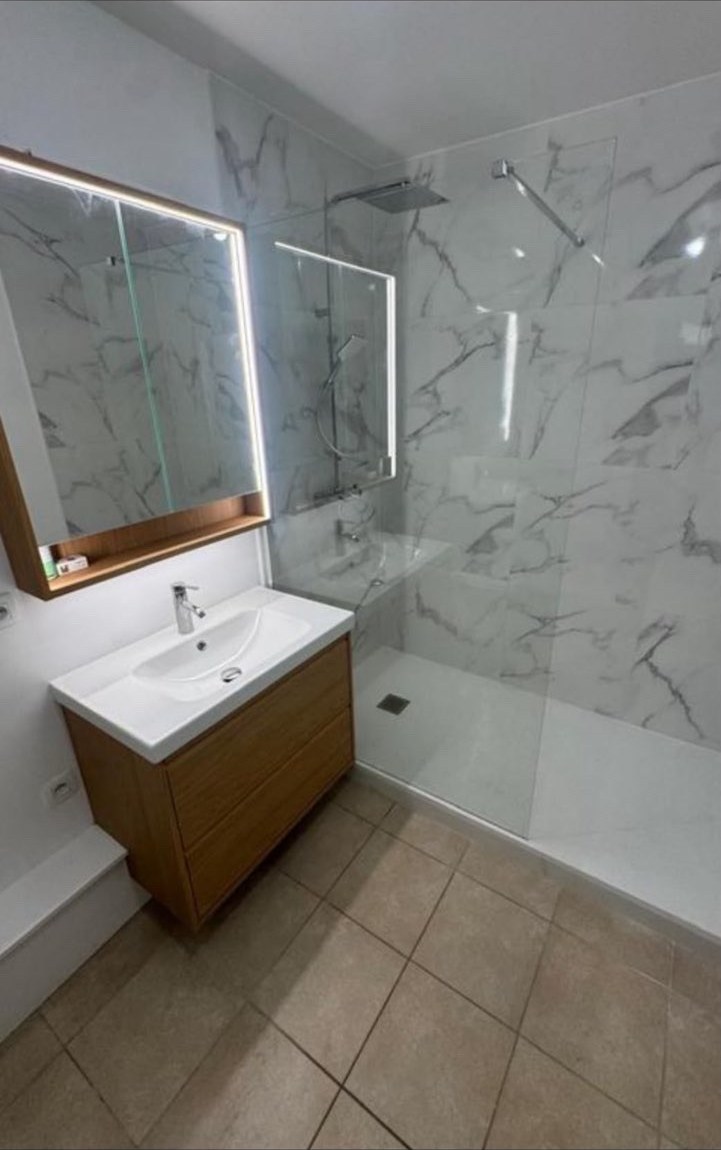 Salle de bain rénovée avec douche, meuble vasque et carrelage marbré