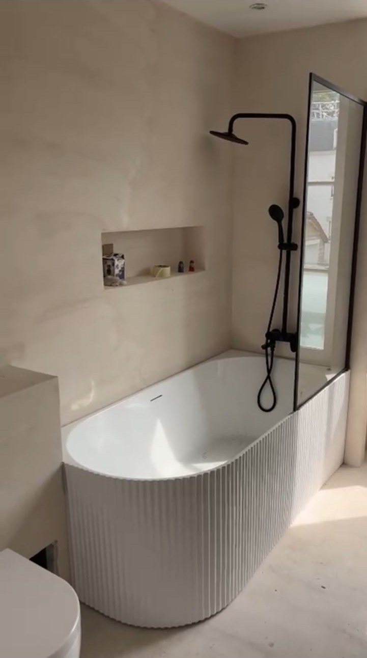 Rénovation de salle de bain avec baignoire arrondie et douche noire